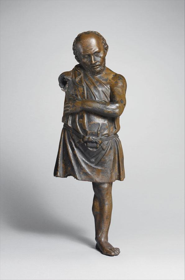Estatua en bronce de un hombre, le faltan el brazo y la pierna derechos, tiene el brazo izquierdo cruzado frente al cuerpo.