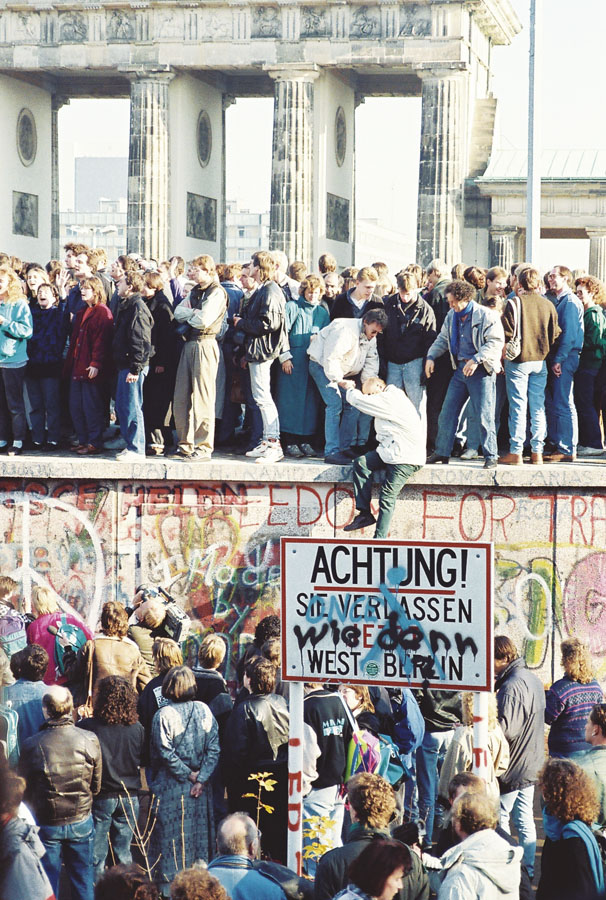 Personas sobre el Muro de Berlín frente a la Puerta de Brandemburgo. Fotografía de Sue Ream, 1989